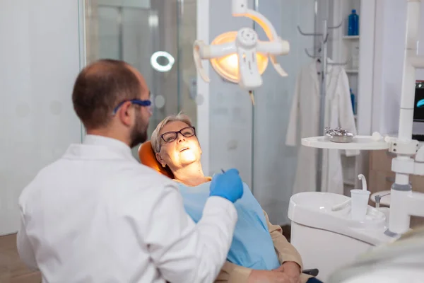 Paciente sênior reparando dente na clínica odontológica — Fotografia de Stock