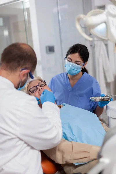 Стоматолог с ассистентом установить имплантат в рот пациента — стоковое фото