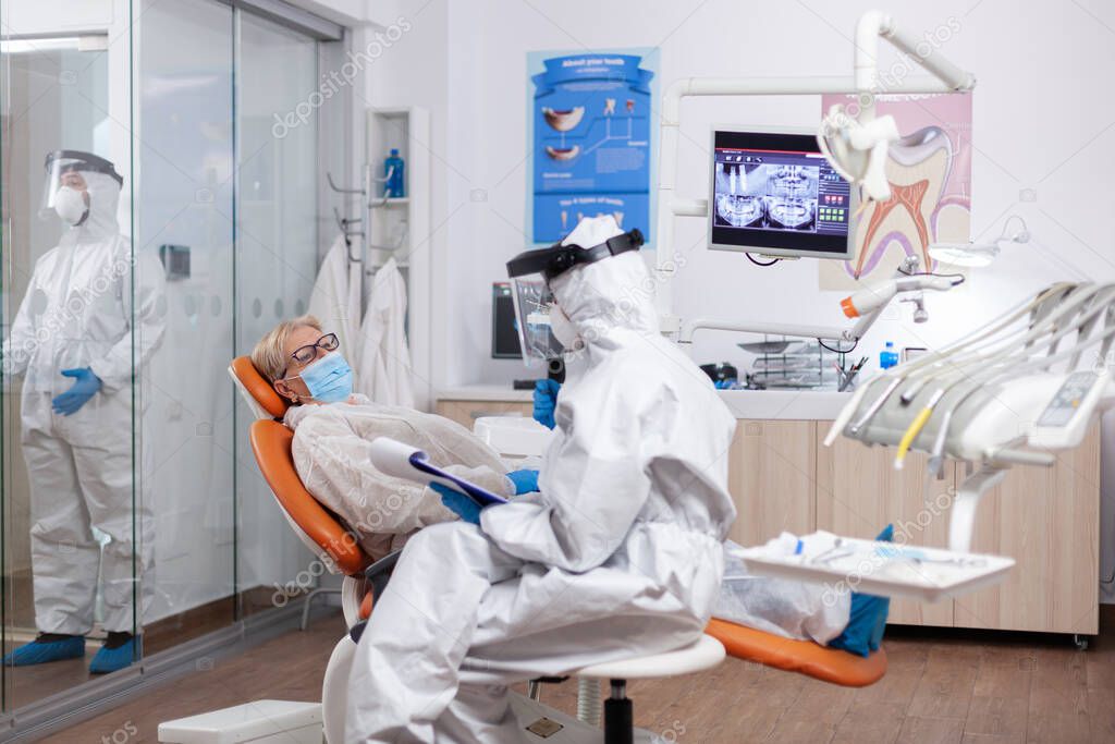 Dentist assitatnt questioning patient wearing protective equipment