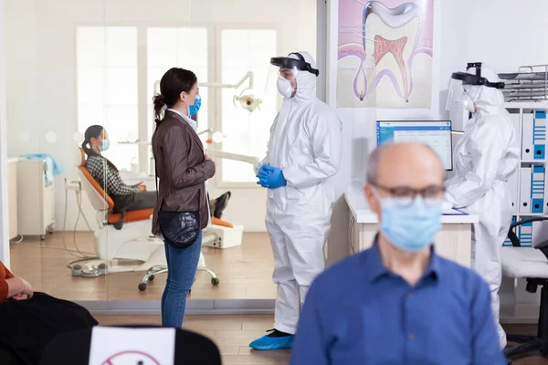Врач-дантист, одетый в костюм, обсуждает с пациентом — стоковое фото