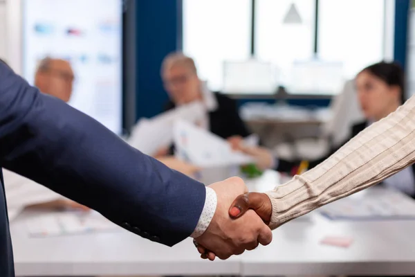 Close up de parceiros de negócios multirraciais em pé na frente da mesa de conferência apertando as mãos — Fotografia de Stock