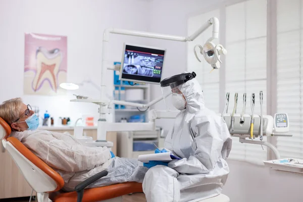 Senior patiënt presenteren tanden pijn dragen van hazmat pak tegen coronavirus — Stockfoto