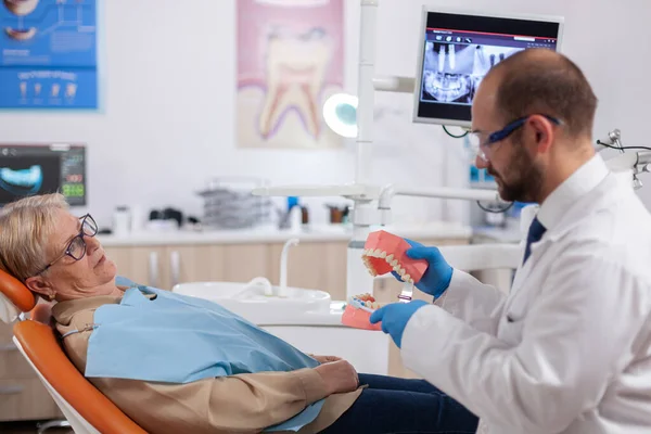 Стоматолог держит модель полости рта с зубами — стоковое фото
