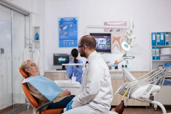 치과 의사가 노인 치과 방사선 촬영을 보고 검사하는 모습 — 스톡 사진