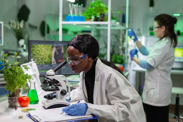 Médico bioquímico africano examinando pruebas químicas con microscopio —  Fotos de Stock