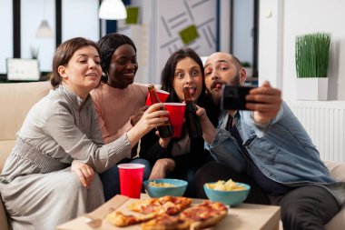 Bir grup iş arkadaşı akıllı telefondan selfie çekiyor.