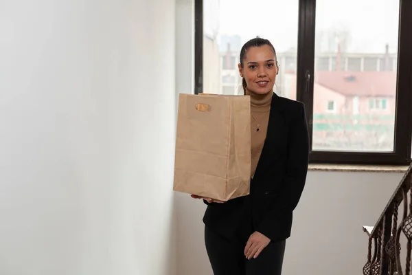 Girişimci şirket ofisinde merdivenleri çıkan iş kadını hazır yemek torbası taşıyor. — Stok fotoğraf