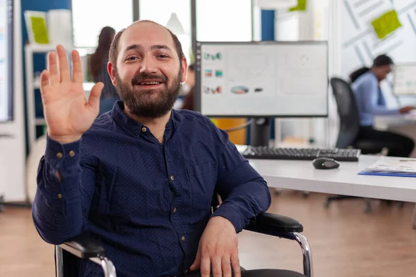 Empresario inmovilizado sentado en silla de ruedas discutiendo en videocall saludando —  Fotos de Stock