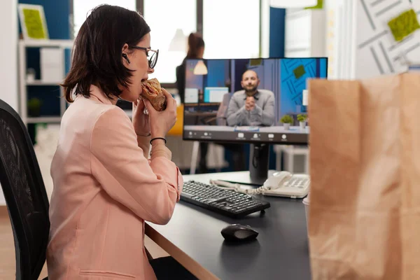 Empresária comer entrega takeaway sanduíche durante videocall conferência on-line — Fotografia de Stock
