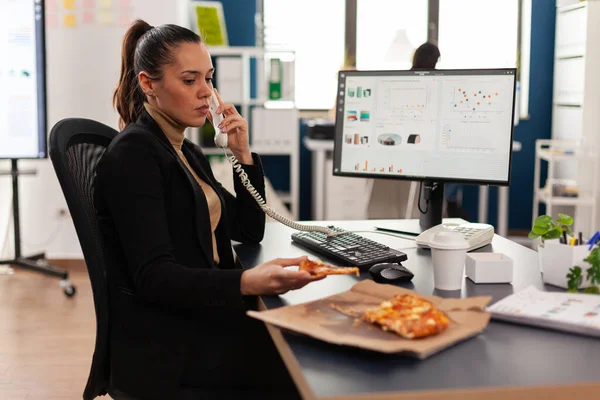 Multitasking zakenvrouw praten op vaste lijn uitleggen bedrijf grafieken aan collega op afstand — Stockfoto