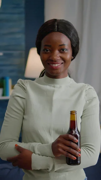 Potrait de mujer afroamericana sonriendo a la cámara mientras sostiene la botella de cerveza — Foto de Stock