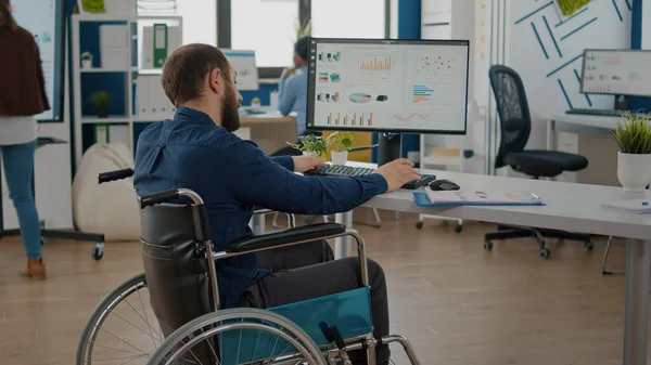 Gestionnaire paralisé travaillant dans un bureau d'affaires en démarrage assis en fauteuil roulant — Photo