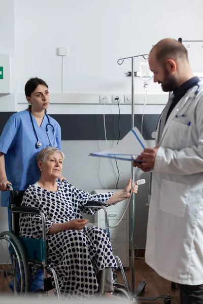 Elderly sick patient sitting in hospital wheelchair getting treatment