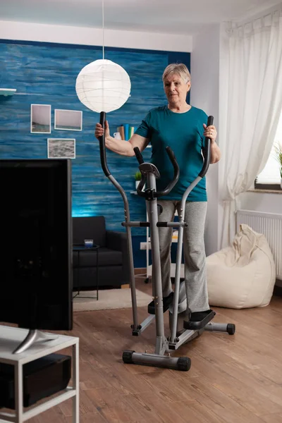 Focused senior woman working at legs muscle resistance cycling bicycle machine — Stock Photo, Image