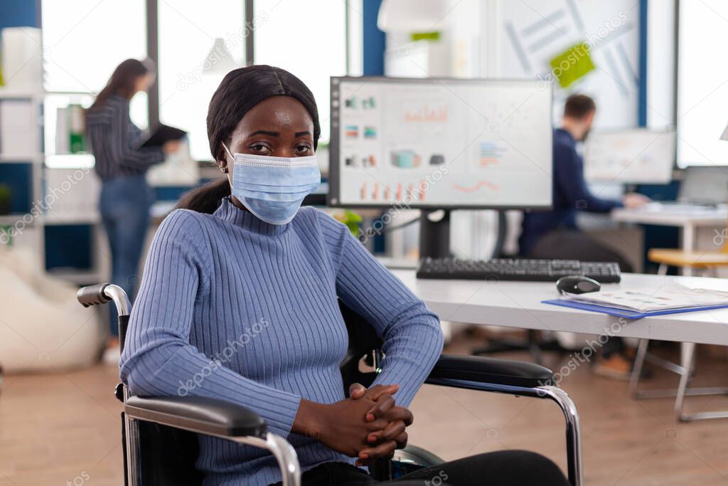 Handicapped african employee looking at camera wearing protection mask