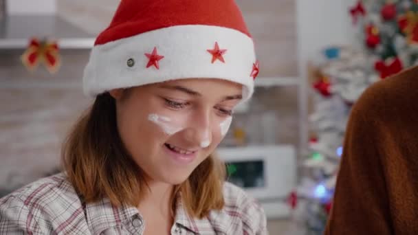 Porträt einer Enkelin mit Mehl im Gesicht, die Weihnachtsmütze trägt und köstliches Dessert zubereitet — Stockvideo