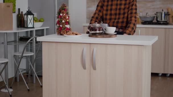 Retrato do avô vestindo chapéu de Papai Noel sentado em xmas cozinha decorada — Vídeo de Stock