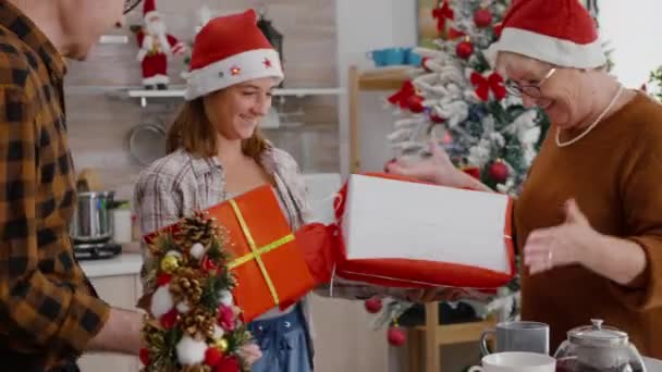 Feliz nieta sorprendiendo a los abuelos con regalo regalo de envoltura de Navidad — Vídeo de stock