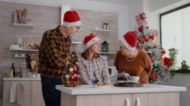 Büyükannem ve büyükbabam üzerinde kurdele olan ambalajlı Noel hediyesini torunuma veriyorlar.