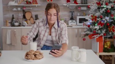 Mutlu kız kış tatilinin tadını çıkarıyor. Xmas 'ın süslü mutfağında oturmuş akıllı telefonlara bakıyor.