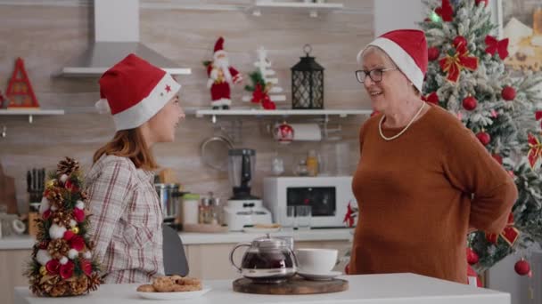 Feliz familia vistiendo sombrero de Santa Sorprendente unos a otros con regalo de Navidad envoltura — Vídeos de Stock