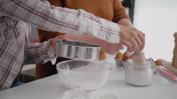 Η γιαγιά μαθαίνει στην εγγονή πώς να κοσκινίζει το αλεύρι με σουρωτήρι κουζίνας — Αρχείο Βίντεο