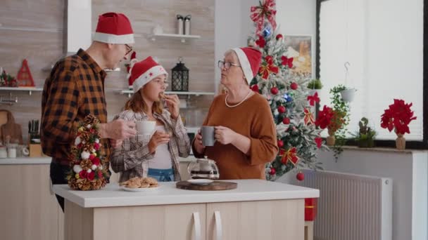 Feliz familia vistiendo sombrero de santa celebración de Navidad día de fiesta comiendo galletas de chocolate horneado — Vídeo de stock