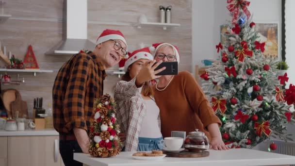在圣诞节的庆祝活动中，孙女用智能手机和祖父母一起自拍 — 图库视频影像