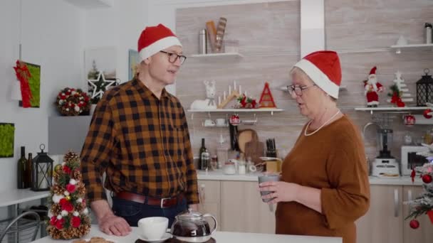 Çevrimiçi video görüşmesi sırasında telefon kullanarak Noel Baba şapkalı mutlu aile uzaktan arkadaşlarını selamlıyor. — Stok video