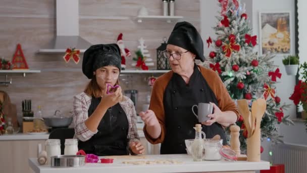 Бабуся пояснює внучці, як зробити традиційний шліфувальний десерт з пряників. — стокове відео