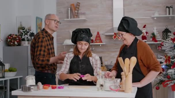 Grandchild standing at table in xmas decorated culinary kitchen making delicious gingerbread dessert — Stock Video