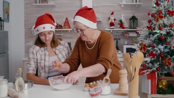 Vnučka s vnučkou lámání vejce v misce s moukou ingredience — Stock video