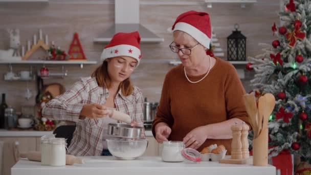 Mujer mayor enseñando nieto que a enderezar ingrediente de harina en tazón — Vídeos de Stock