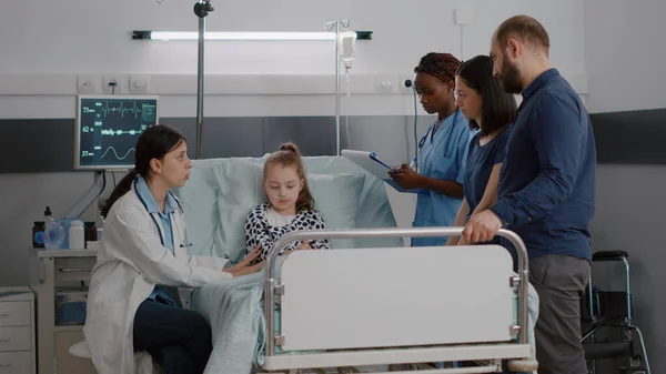 Physician pediatric doctor monitoring disease symptoms while african american nurse checking IV drip bag