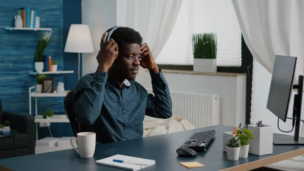 Szabadúszó afrikai etnikai feltett fejhallgató munka közben otthonról — Stock Fotó