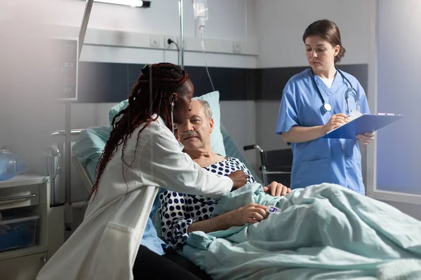 Afrikanischer Arzt mit Stethoskop hört älteren Mann Herz — Stockfoto