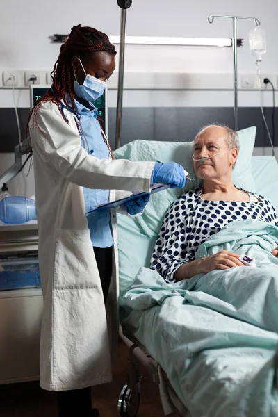 African american doctor with surgical mask reading diagnosis from clipboard