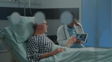 Afro-Amerikalı doktor, hastaya X-ray 'i tabletle açıklıyor.