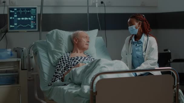 Африканский американский медик разговаривает с больным пациентом в больнице — стоковое видео