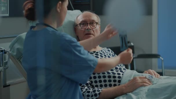 Медсестра объясняет больному пациенту результаты рентгена — стоковое видео