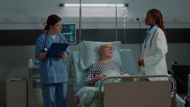 Multi-etnisch medisch team controleert pols op patiënt — Stockvideo