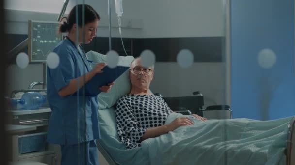 Caucasian nurse checking on elder patient in hospital ward — Stock Video