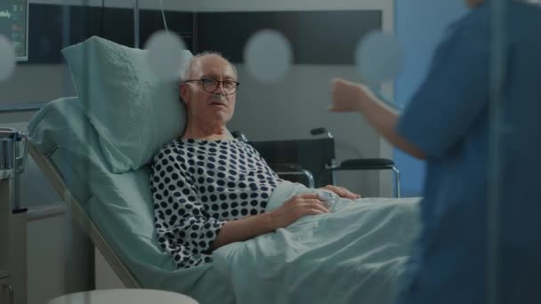 Hemşire hastane koğuşundaki hastaya röntgen sonuçlarını gösteriyor. — Stok video