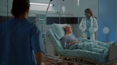 Hastane koğuşundaki hasta hasta için tekerlekli sandalye hazırlayan hemşire.