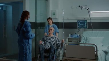 Afrikalı Amerikalı doktor tekerlekli sandalyedeki hastayı alıyor.