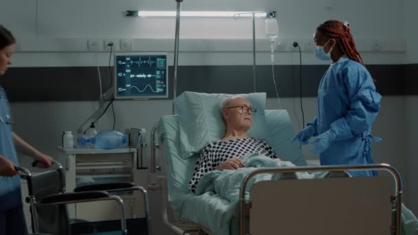 Infermiera che porta la sedia a rotelle al paziente nel letto del reparto ospedale — Video Stock