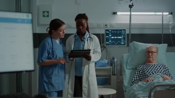 Multietnisk sjuksköterska och läkare undersöker tabletten för tester — Stockvideo