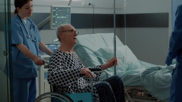 Paciente sênior saindo da enfermaria hospitalar em cadeira de rodas — Vídeo de Stock