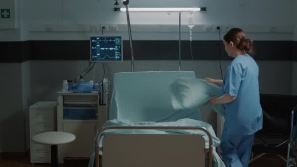 Pielęgniarka medyczna organizująca koc i poduszkę na łóżku szpitalnym — Wideo stockowe