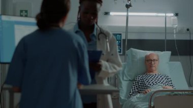 Afrikalı Amerikalı doktor, hemşirelere hasta teşhisi hakkında konuşuyor.